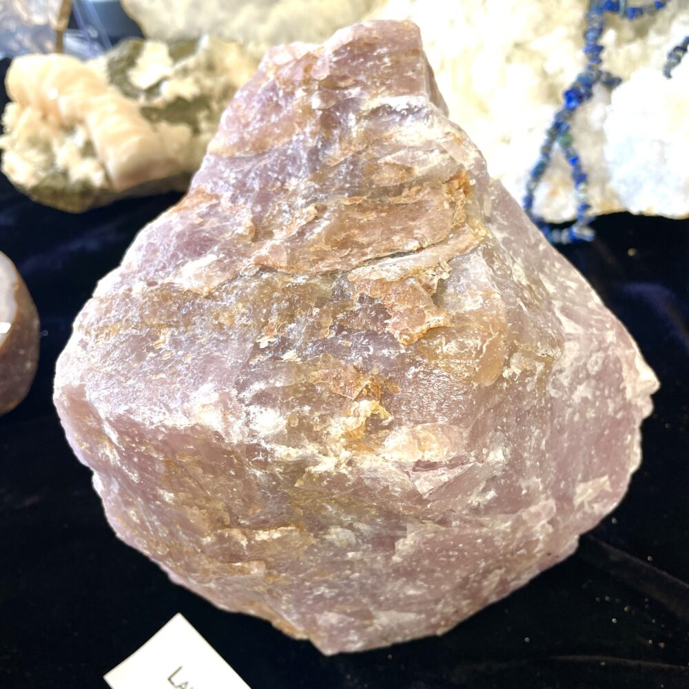 A hefty 11.1 lb (5 kg) boulder of Lavender Cherry Rose Quartz shows light purple tones, resting among other minerals—an impressive piece.
