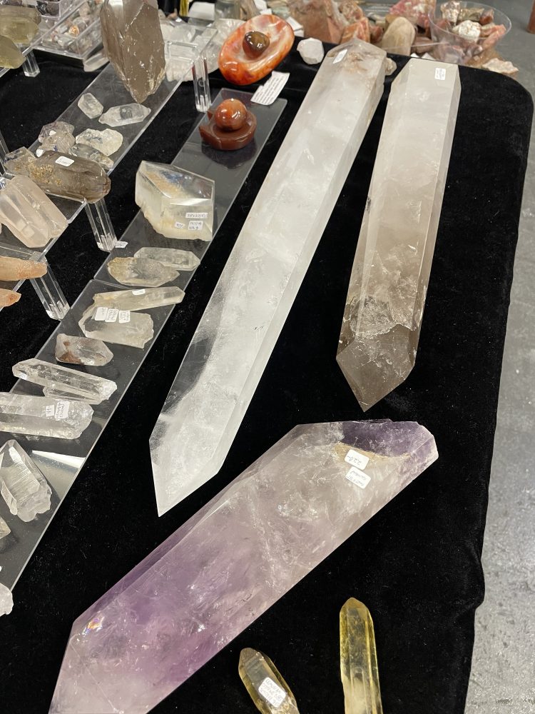 A rare Self Healed Lemurian Quartz Crystal showing Hematite (5.5 long) is displayed on a black tablecloth with price tags.