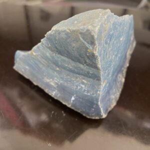 A 14.5 oz (406g) piece of Leland Blue Slag Glass, showing several beautiful blue shades, rests on a dark reflective surface.