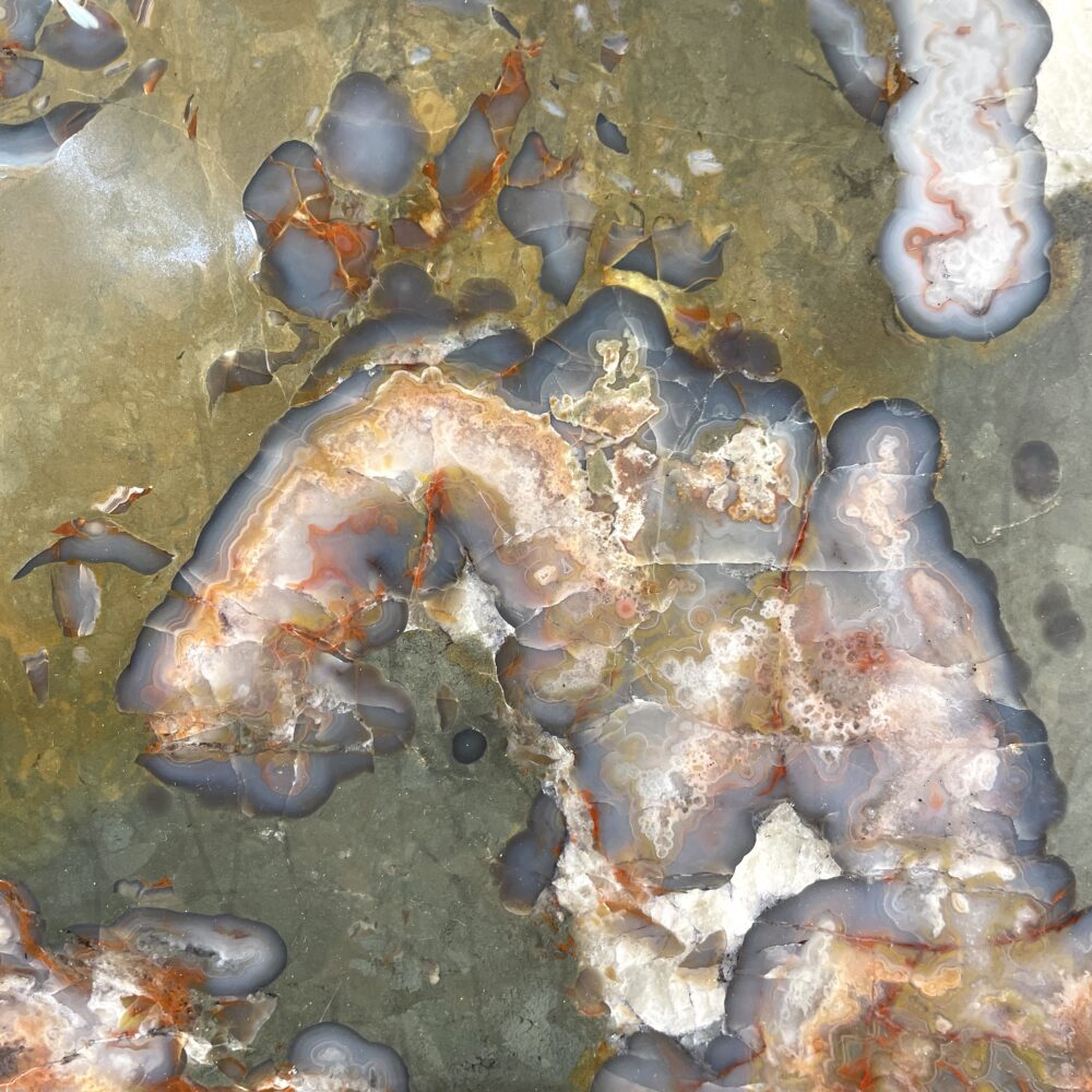 Close-up of the Kentucky Agate Cut Geode Nodule, 4.5 in, highlights swirling yellow, gray, and white patterns with translucent and crystalline areas, showcasing the unique beauty of this polished specimen.