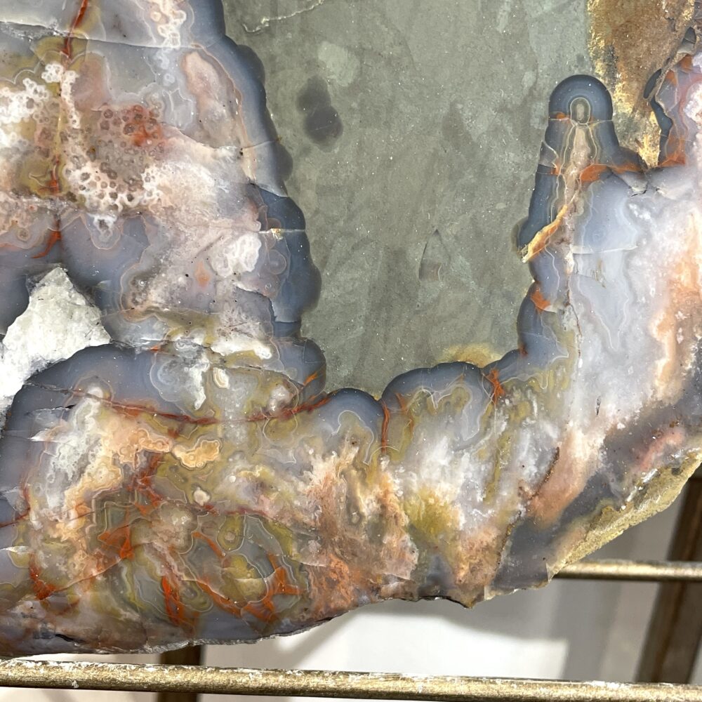 Close-up of the Kentucky Agate Cut Geode Nodule, 4.5 in, featuring polished yellow, gray, and white mineral layers with a rough, jagged edge—showcasing its unique natural beauty.