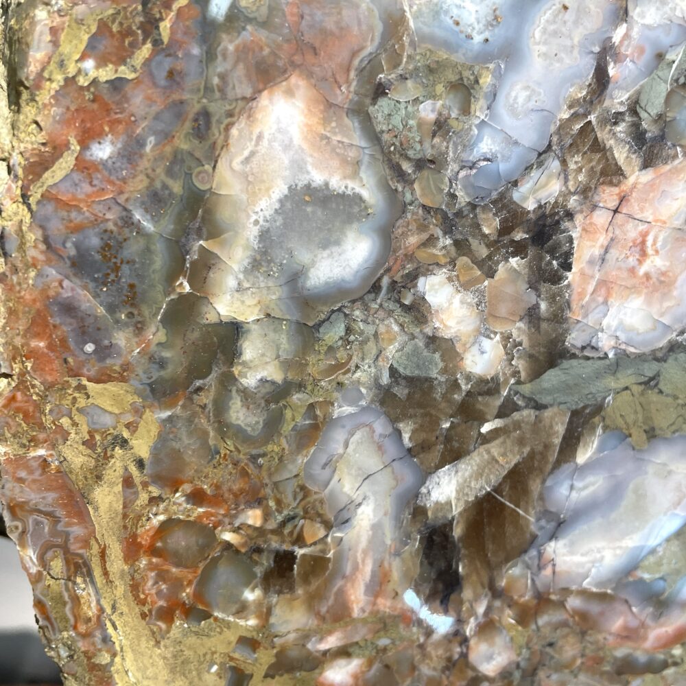 Close-up of the Huge Giant Kentucky Agate Geode Nodule Polished, displaying vibrant mineral patterns in orange, gray, brown, and blue with visible fractures and veins.