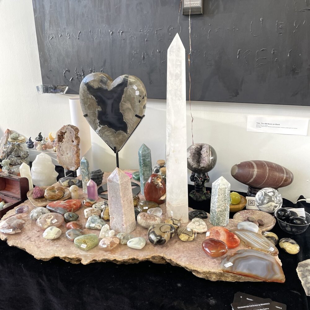 A monumental 19.8-inch quartz crystal wand specimen is displayed on a tabletop against a black background.