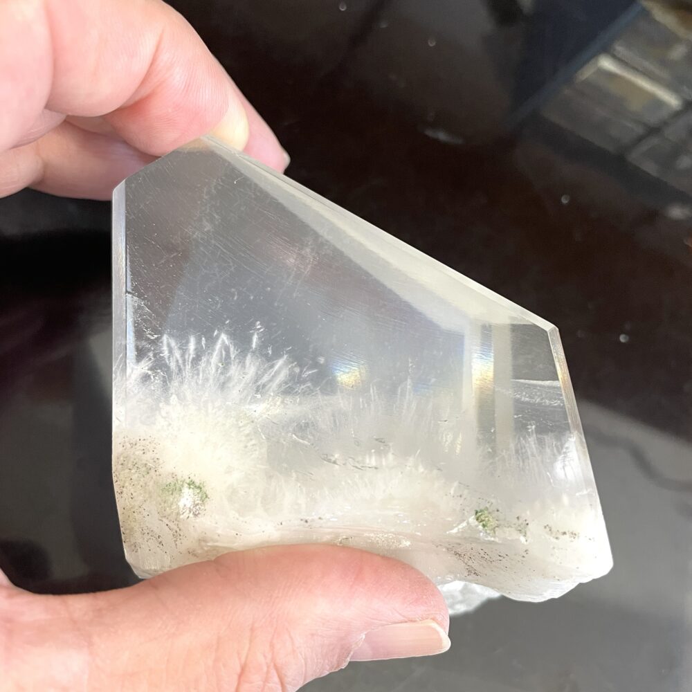A hand holds a Rare Okenite inside Optical Calcite (Icelandic Spar) from India, 1 lb 4.9 oz (593g), against a dark background.