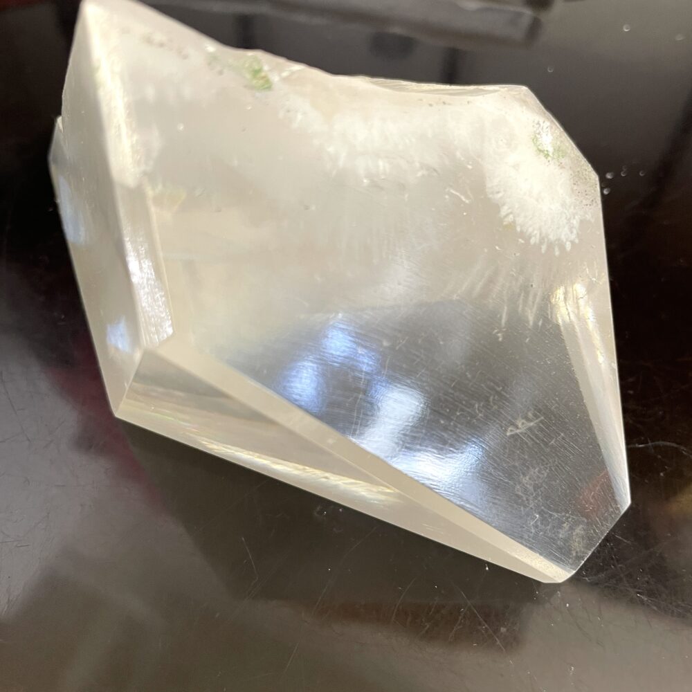 A rare Okenite inside Optical Calcite specimen from India, weighing 1 lb 4.9 oz, sits on a shiny black surface with intriguing texture.