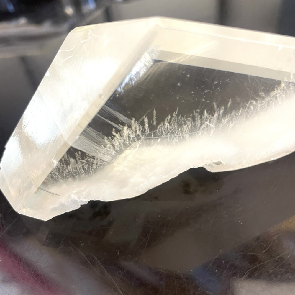 A rare Okenite inside Optical Calcite from India, 7.5 oz, on a black reflective surface highlighting its unique clarity.