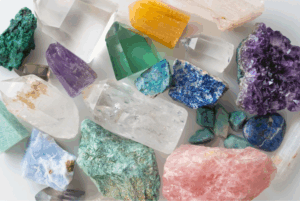 Colorful crystals and minerals, displayed on a white surface, commonly valued in spiritual practices as healing stones.